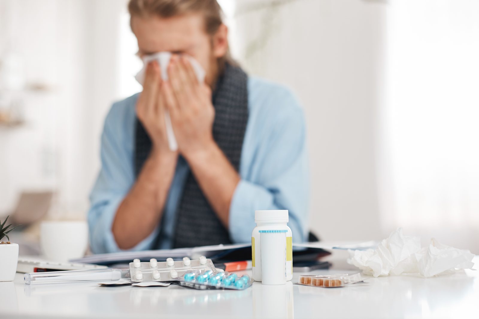 Muž smrká u stolu s léky a vitamíny